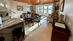 Une cuisine spacieuse avec un plafond en bois, un coin repas avec une table et des chaises, et un salon avec un canapé et une table basse.