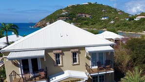 Une grande maison à deux étages, avec un toit blanc, de nombreux balcons et une entrée en pierre.