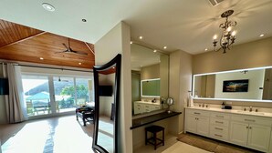 Une salle de bain moderne avec un grand miroir, un lustre et une vue sur l’extérieur.