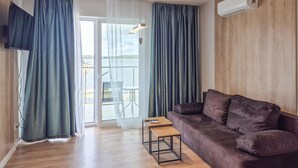 A living room with a brown sofa, a small wooden table, and a TV mounted on the wall. - Stunning apartment in Insko with sauna (Insko)