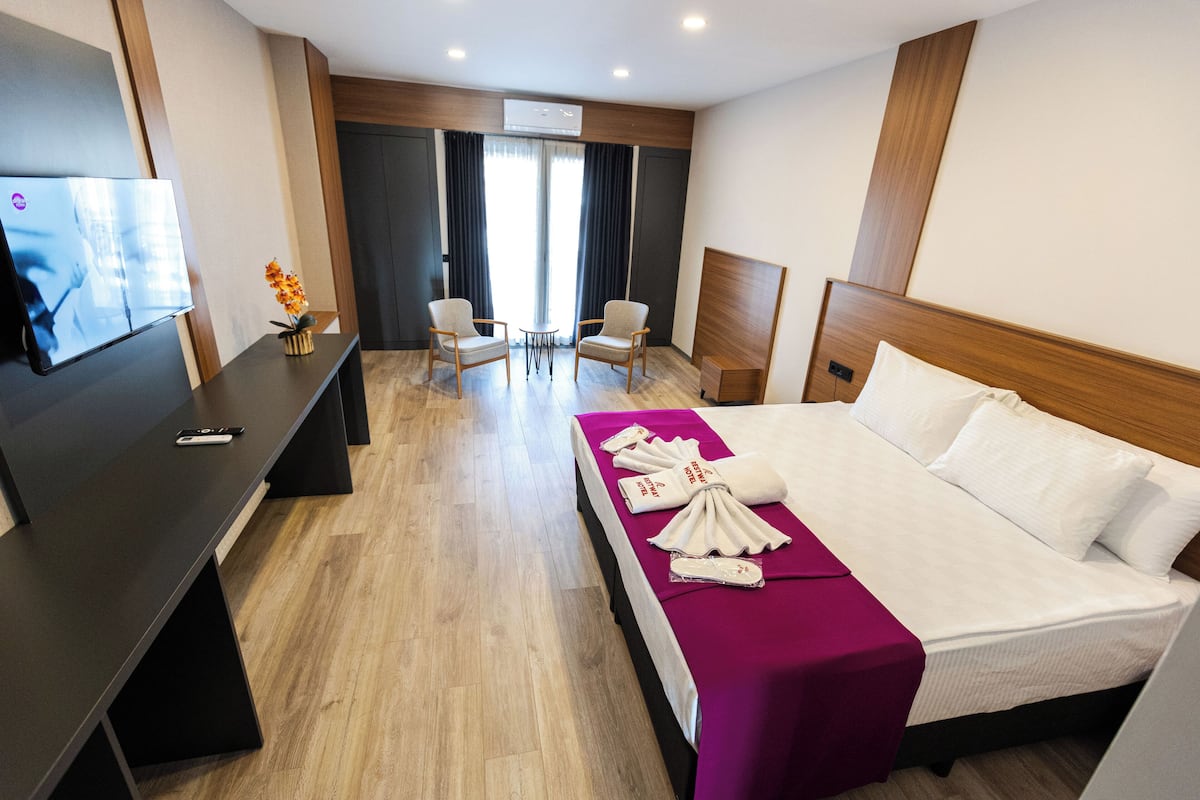 A hotel room with a bed, a TV, a desk, and two chairs.