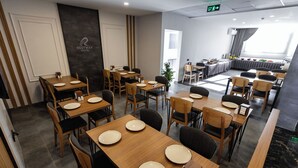 A hotel dining area with multiple tables and chairs, a reception desk, and a buffet setup. - Restway Hotel (Izmir)