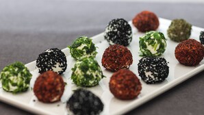A white rectangular plate with various food items, including some with green leafy toppings and others with black and red coatings. - Restway Hotel (Izmir)