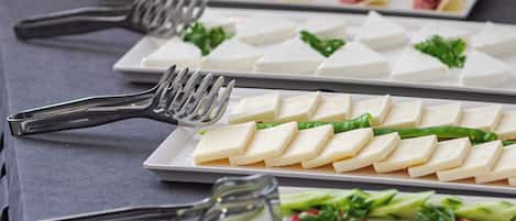 Una mesa de buffet con diversos alimentos, incluyendo queso, verduras y carne.