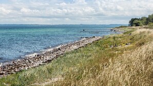 Un paisaje costero con costa rocosa, zonas de hierba y una vista despejada del mar.