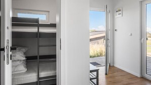 Una habitación con literas, una puerta corrediza a un balcón y una pequeña mesa.