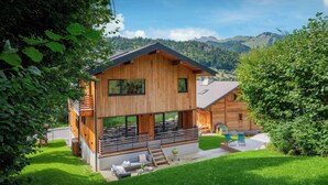 A modern wooden house with a balcony, a small deck, and a well-maintained lawn.