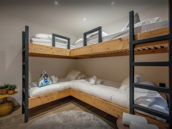 A bunk bed room with a wooden floor, a small plant, and a white rug.