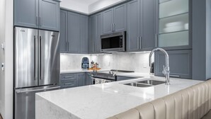 A modern kitchen with grey cabinets, stainless steel appliances, a marble countertop, and a built-in oven. - Luxurious Home In The Village Core - Hot Tub! (Sun Peaks)