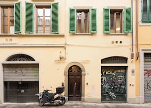 A building with a closed garage door, a motorcycle parked in front, and a door with graffiti.