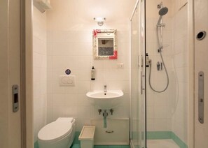 A bathroom with a toilet, sink, and glass-enclosed shower.