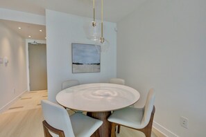 Ein moderner Essbereich mit einem runden Tisch, vier Stühlen, einer Pendelleuchte und einem Gemälde an der Wand.