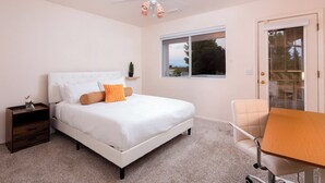 Une chambre à coucher comprenant un lit, une table de chevet, une chaise, une table, un ventilateur de plafond et une fenêtre donnant sur un beau paysage.