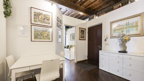 A room with a white table and chairs, wooden flooring, a white cabinet, and framed artwork on the walls. - Sauro River View By MMega (Firenze)