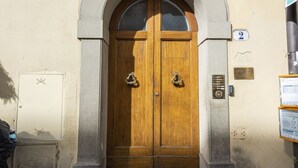 A double wooden door with a metal handle, flanked by stone arches, and a small plaque above the door. - Sauro River View By MMega (Firenze)