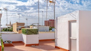 A rooftop terrace with a white wall, a door, and a small garden area.