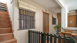A staircase leading to a landing with a black picket fence, a window with bars, and a radiator.
