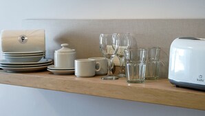 Eine Küchenarbeitsplatte mit weißen Geschirr, einer Kaffeemaschine und mehreren Gläsern.