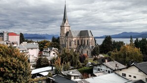 A historic church with a tall spire, surrounded by residential buildings and a lake.