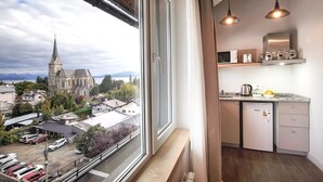 A modern kitchen with a view of a church and mountains.