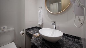 A bathroom with a white sink, a mirror, a towel rack, and a hairdryer.
