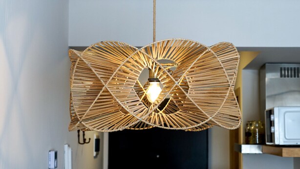 Un luminaire suspendu en rotin tressé, avec une ampoule, dans une cuisine au style moderne.