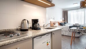 Une chambre d’hôtel compacte dotée d’une kitchenette, d’un lit avec vue et d’un petit coin repas.