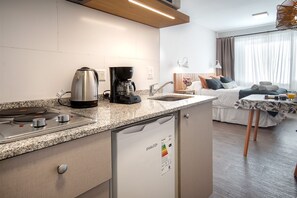 Cozy retreat with a kitchenette, featuring a bed, coffee maker, kettle, and refrigerator.