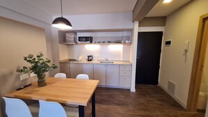 A compact kitchen with a microwave, sink, and a dining area with a table and chairs.