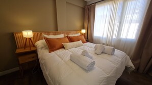 A hotel room with a large bed, two bedside tables with lamps, and a window with curtains.
