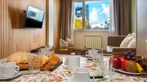 Ein Essbereich mit einem für das Frühstück gedeckten Tisch, einschließlich Croissants, Obst und Kaffee.