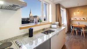 A modern kitchen with a large window, a view of a church, a dining area with a table and chairs, and a hanging light fixture. - Mutisia flat with terrace and lake views in Bariloche (San Carlos de Bariloche)