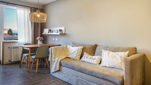 A cozy living room with a sofa, a dining table, and a pendant light. - Mutisia flat with terrace and lake views in Bariloche (San Carlos de Bariloche)