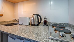 Een keuken met granieten aanrecht, een broodrooster, een waterkoker en een kookplaat met twee branders.