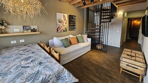 A modern bedroom with a large bed, a wooden ceiling, a staircase, and a TV. - Montaña apartment with lake view and parking in Bariloche (San Carlos de Bariloche)