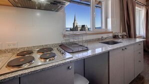 A modern kitchen with a gas stove, a sink, and a window with a view of a church and mountains. - Montaña apartment with lake view and parking in Bariloche (San Carlos de Bariloche)