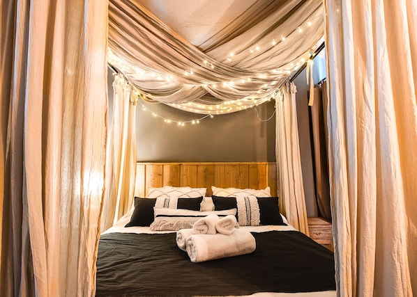 A bed with a wooden headboard, black and white bedding, and a rolled towel.