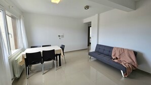 Un amplio salón con una mesa de comedor, sillas, un sofá y un radiador.
