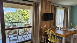 Een kamer met balkon, houten meubels, een televisie en een bed.