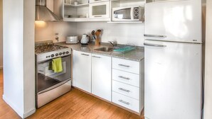 Een kleine keuken met een fornuis, oven, magnetron en koelkast.