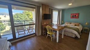 Een kamer met balkon, bed, bureau en televisie.