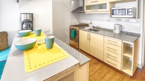 A compact kitchen with a gas stove, microwave, and coffee maker.