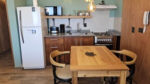 A compact kitchen with a refrigerator, microwave, stove, and wooden table with chairs. - Suizo II Romantic apartment with Nahuel Huapi Lake (San Carlos de Bariloche)