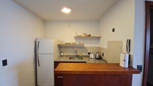 A compact kitchen with a refrigerator, sink, countertop, and wooden cabinets. - Swiss IV apartment with an impressive lake view Nahuel Huapi (San Carlos de Bariloche)