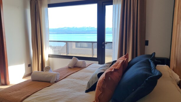 A hotel room with a bed, a view of the sea, and a balcony. - Swiss IV apartment with an impressive lake view Nahuel Huapi (San Carlos de Bariloche)
