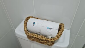 Un vàter amb rotllo de paper higiènic embolcallat en una cistella de vimbles.