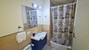 Ein Badezimmer mit Waschbecken, Spiegel, Handtuchhalter und Duschvorhang.