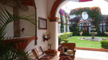 A cozy indoor seating area with a view of a well-manicured garden and a fountain.