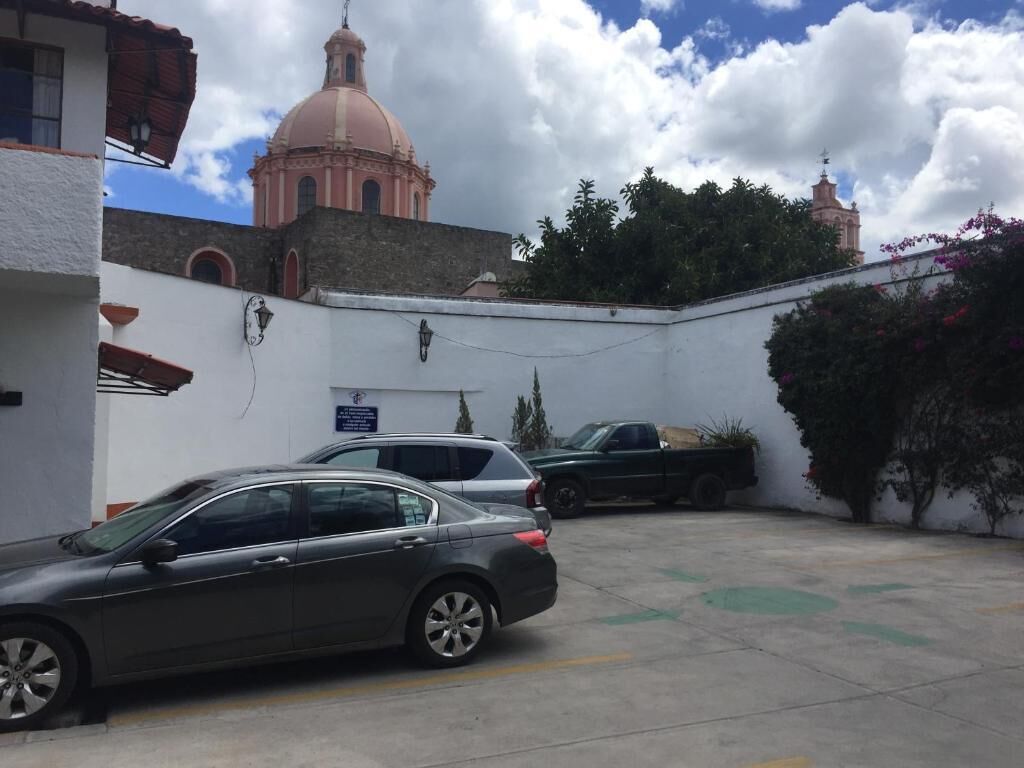 Un estacionamiento con un coche y un camión, un edificio con cúpula y cielo despejado.