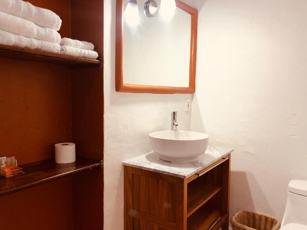Een badkamer met een houten wastafelmeubel, een witte wasbak en een spiegel met houten lijst.